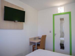 a room with a table and a tv on a wall at Hotel Restaurant Les Jardins D'Epône in Épône