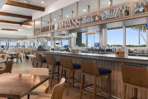 un restaurante con un bar con mesas y sillas en Compass Hotel by Margaritaville Anna Maria Sound en Bradenton