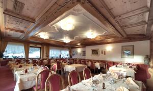 una sala da pranzo con tavoli, sedie e soffitto di Hotel Flora Alpina a Campitello di Fassa