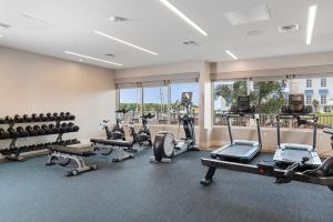 a gym with treadmills and exercise equipment and windows at Compass Hotel by Margaritaville Anna Maria Sound in Bradenton