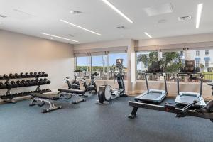 einen Fitnessraum mit Laufbändern, Trainingsgeräten und Fenstern in der Unterkunft Compass Hotel by Margaritaville Anna Maria Sound in Bradenton