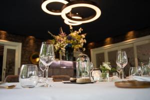 デルデンにあるLandgoed Hotel & Restaurant Carelshavenのシャンデリア付きのワイングラス付きテーブル