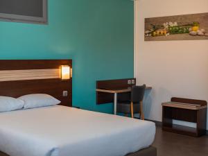 a bedroom with a bed and a desk and a table at Hotel Restaurant Les Jardins D'Epône in Épône