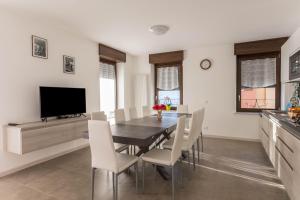 une salle à manger avec une table, des chaises et une télévision dans l'établissement Casa Balansina, à Brenzone