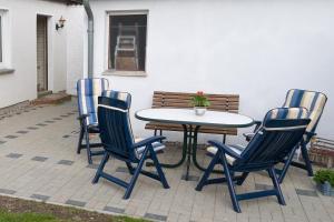 ein Tisch und vier Stühle um einen Tisch und eine Bank in der Unterkunft Preisgünstige und gemütliche Ferienwohnung am Wieker Bodden in Wiek auf Rügen 