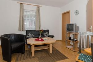 ein Wohnzimmer mit einem Sofa, einem TV und einem Tisch in der Unterkunft Ferienwohnung für 2 Erwachsene auf Rügen in Groß Banzelvitz