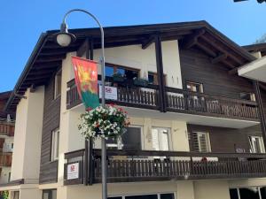 ツェルマットにあるCentral & Elegant Apartments,partially with Fireplace, by Zermatt Rentalの旗と花のバルコニー付きの建物