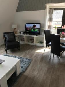 a living room with a flat screen tv and chairs at Andrea-OG in Büsum