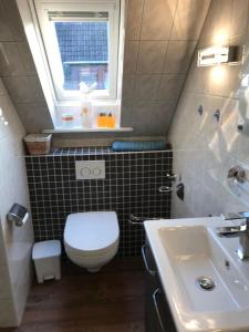 a bathroom with a toilet and a sink and a window at Andrea-OG in Büsum