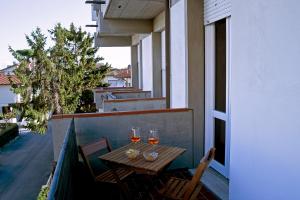 einen Tisch mit zwei Gläsern Wein auf dem Balkon in der Unterkunft Ampio, elegante apt con aria condizionata e bici gratis in Viareggio
