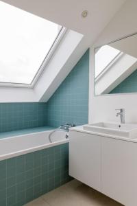 a bathroom with a tub and a sink and a skylight at Savoie in Brussels