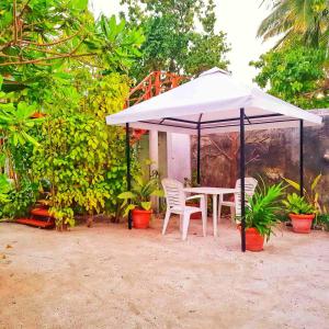 a white table and chairs under a white umbrella at Sunset Beach View in Dhangethi