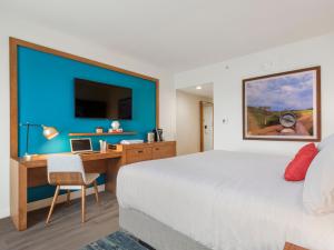 a bedroom with a bed and a desk with a laptop at Compass Hotel by Margaritaville Anna Maria Sound in Bradenton