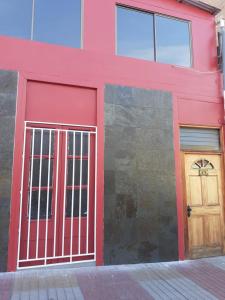 a red building with a gate and a door at Hostal Iria in Antofagasta