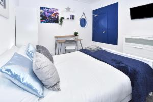 a bedroom with a white bed with blue pillows at Townhouse @ 42 Minshull New Road Crewe in Crewe