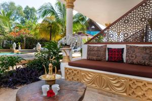 a patio with a bench and a table and a pool at Natural Kendwa Villa in Kendwa