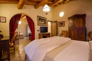 a bedroom with a large white bed and a television at Hotel Corte Vecchia in San Prospero 