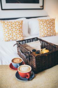 a basket and two cups of coffee on a bed at Caffeine&Machine in Stratford-upon-Avon