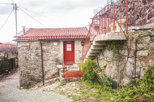 een stenen huis met een rode deur en een trap bij Casa Nova de Germil in Ponte da Barca