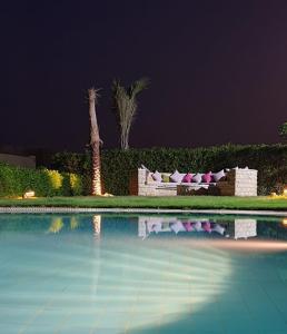 uma piscina à noite com um sofá e palmeiras em Byoum Vacation House em Fayum