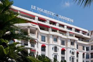 a white building with a sign on top of it at Hôtel Barrière Le Majestic Cannes in Cannes