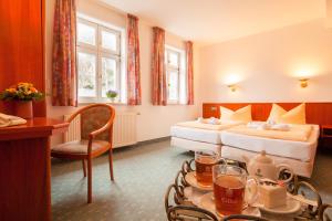 クヴェードリンブルクにあるホテル ドームシャッツのベッド2台とテーブルが備わるホテルルームです。