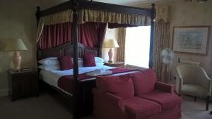
a bed room with a red bedspread and a red canopy at Orton Hall Hotel & Spa in Peterborough
