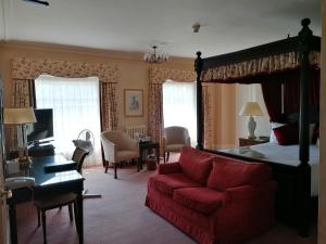 a bedroom with a bed and a red couch at Orton Hall Hotel & Spa in Peterborough