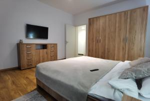 Tohanu NouにあるEdanApartmentsのベッドと壁にテレビが掛かった寝室