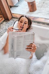 a woman sitting in a bath tub reading a newspaper at El Llorenc Parc de la Mar - Adults Only (+16) in Palma de Mallorca