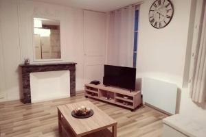 een woonkamer met een tv en een tafel en een klok bij Bel appartement 50m2 en plein centre de Saumur in Saumur