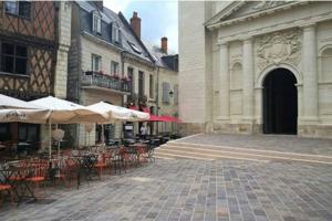 een lege binnenplaats met tafels, stoelen en parasols bij Bel appartement 50m2 en plein centre de Saumur in Saumur