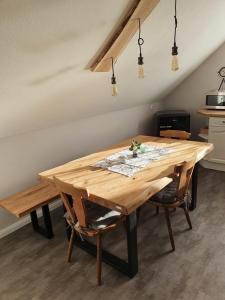 uma mesa de jantar em madeira com 2 cadeiras e luzes em Chickenhill Blackforest, Ferienwohnung Großhans em Bad Wildbad