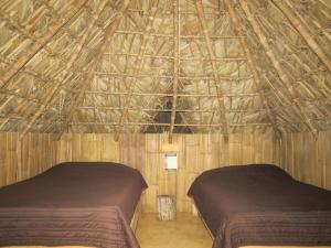 a room with two beds in a bamboo building at Bel-Há Ecoparque in El Naranjo