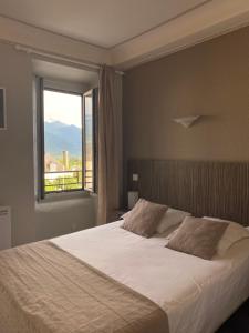 sypialnia z dużym łóżkiem i oknem w obiekcie Hôtel Café les Fleurs w mieście Argelès-Gazost