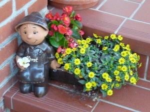 a small statue next to a flower pot with flowers at Letztes Haus vorm Wasser (2) in Strukkamp auf Fehmarn