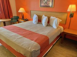 una camera d'albergo con un grande letto con cuscini bianchi di Scottish Inns and Suites- Bordentown, NJ a Bordentown