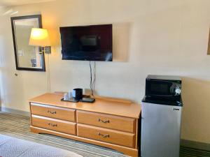 Scottish Inns and Suites- Bordentown, NJ في بوردينتاون: غرفة في الفندق مع تلفزيون وخزانة مع ميكروويف
