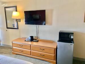 um quarto de hotel com uma televisão e uma cómoda com um micro-ondas em Scottish Inns and Suites- Bordentown, NJ em Bordentown