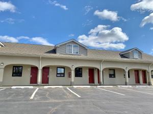 a building with red doors in a parking lot at Scottish Inns and Suites- Bordentown, NJ in Bordentown