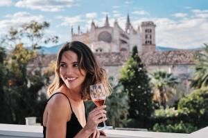 a woman is holding a glass of wine at El Llorenc Parc de la Mar - Adults Only (+16) in Palma de Mallorca