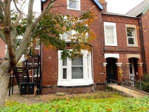 a brick house with a white window and a tree at Spacious Victorian Studio Flat in Doncaster