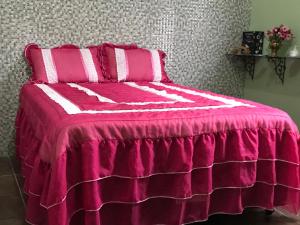 uma cama rosa com lençóis e almofadas cor-de-rosa e branco em hospedagem casa da wal quarto suíte em Goiás