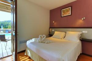 a bedroom with a large white bed and a balcony at Hôtel Les Gabarres in Tour-de-Faure