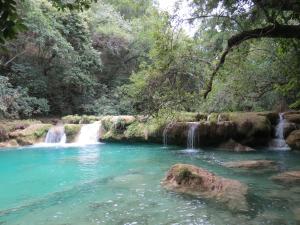 a waterfall in the middle of a river in a forest at Bel-Há Ecoparque in El Naranjo