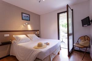 a bedroom with a bed with a hat on it at Hôtel Les Gabarres in Tour-de-Faure