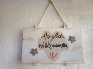 un cartel de madera colgado en una pared con flores en Haus Seerobbe-Erdgeschosswohnung, en Fehmarn 2 fotos más