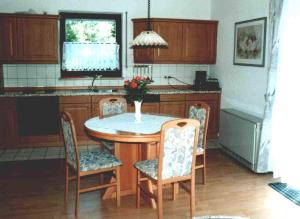 a kitchen with a table and chairs with a vase on it at Haus Seerobbe-Erdgeschosswohnung in Fehmarn