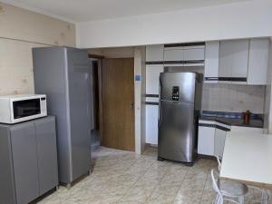 a kitchen with stainless steel refrigerators and a microwave at Apartamento VIP Centro Serra Negra - Familiar in Serra Negra