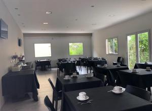 un restaurante con mesas negras, sillas y ventanas en Hotel Vesubio II en Villa Gesell